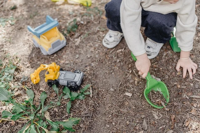 Pack of coffee grounds next to a woman digging a garden.