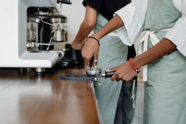 A Barista packing coffee into a press to be ground.