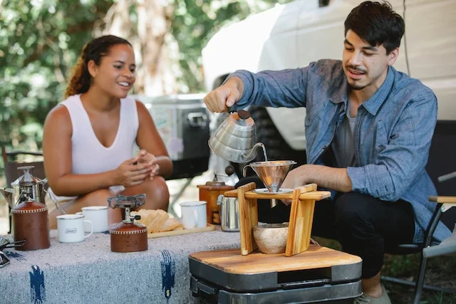 Couple sitting down making a pour over coffee.