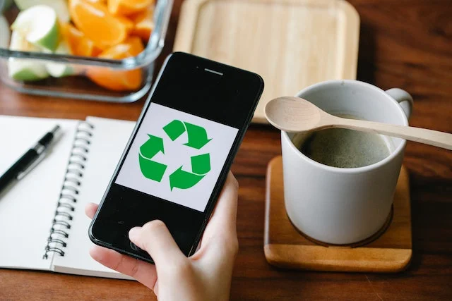 Phone with recycle logo on the screen next to cup of coffee. Indicating the circular economy coffee.